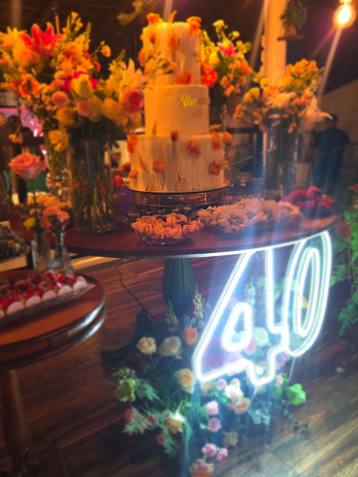 Mesa de doces com bolo floral e letreiro de neon