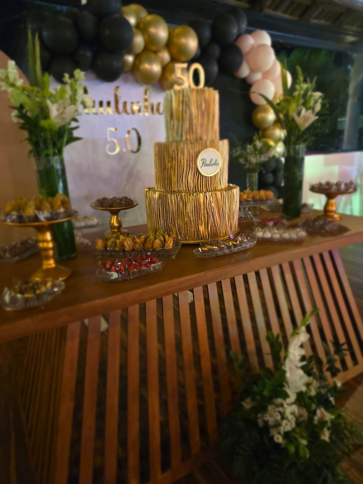 Bolo dourado de aniversário sobre a mesa de doces