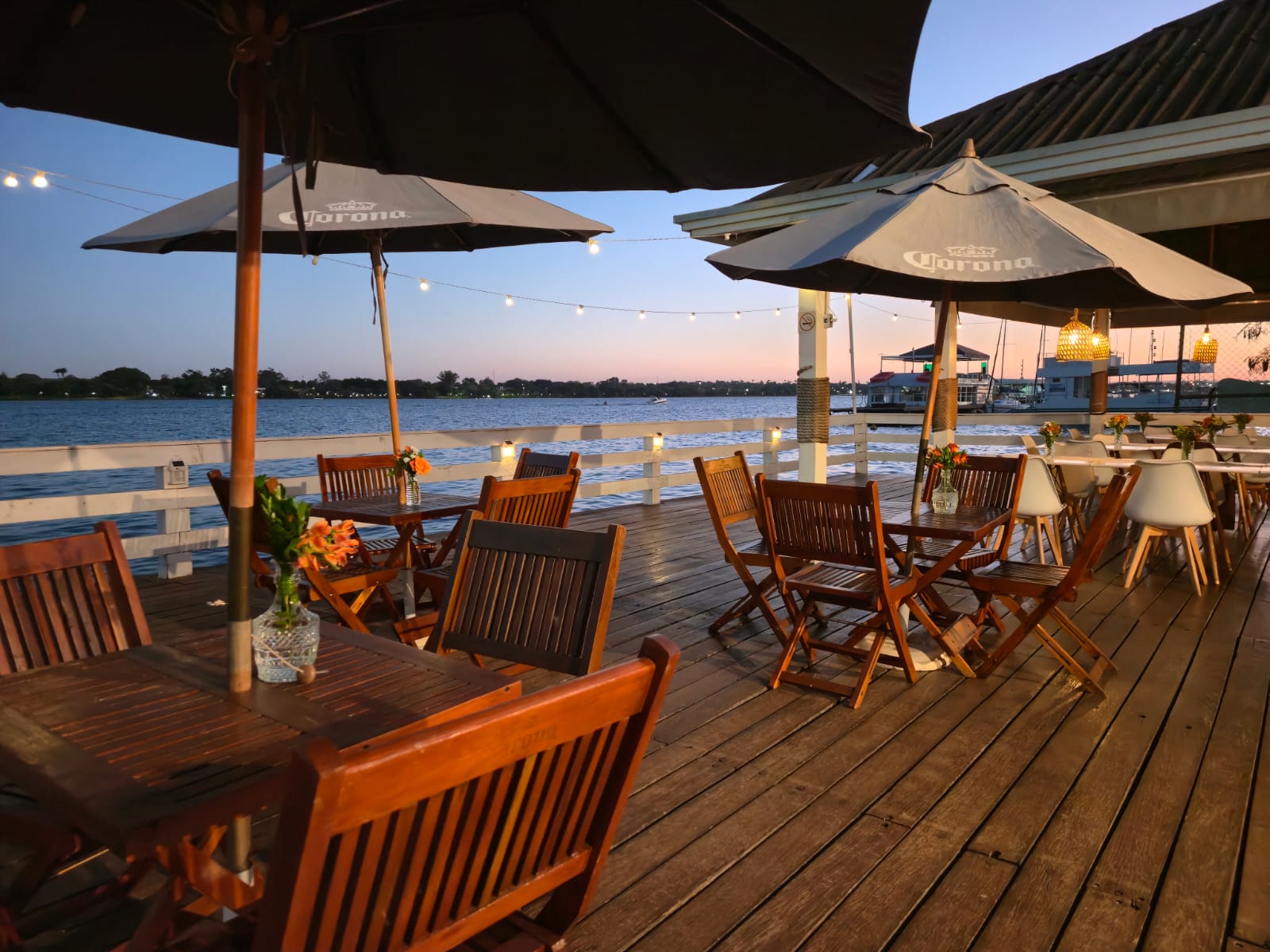 Deck do restaurante ao entardecer, com mesas de frente para o lago