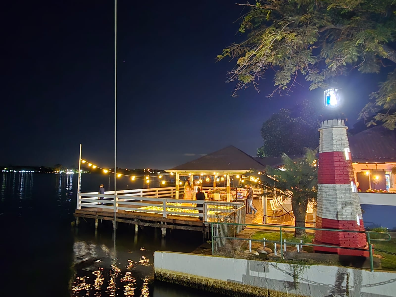 O farol e o píer iluminados à noite à beira do lago